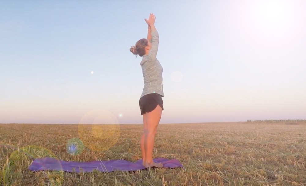 Woman saluting the sun in a field